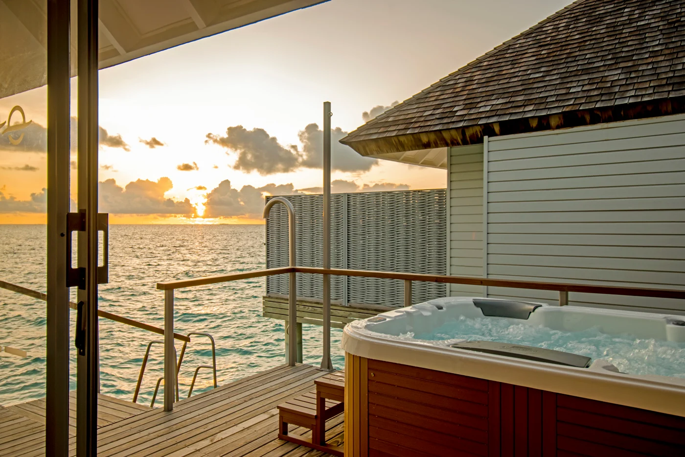Sunset over water villa with hot tub
